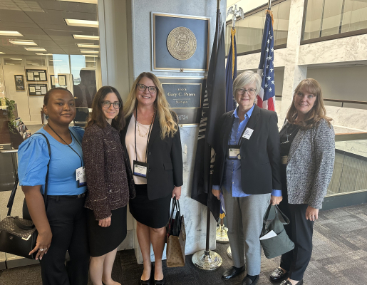 MEJI Staff posing for a photo in front of a plaque for Sen. Peters. From left to right: LaKisha Horn, Laura De Palma, Mireille Phillips, Sarah Slocum, Michelle Danou.