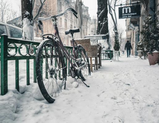 Winter city sidewalk with a bicycle and filled with snow.