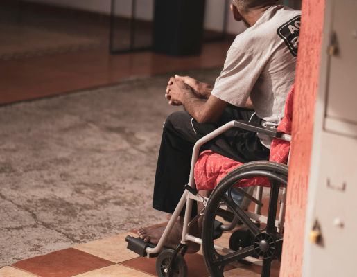 An older adult in a wheelchair facing away.