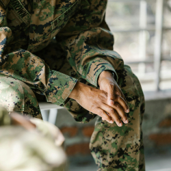 Soldier sitting down wearing camouflage uniform.