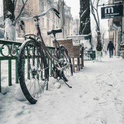 Winter city sidewalk with a bicycle and filled with snow.