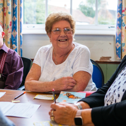 Group of older adults sitting around a table smiling and having conversation.