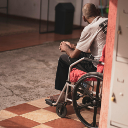 An older adult in a wheelchair facing away.